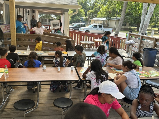 Large outdoor community workshop with youth seated at tables
