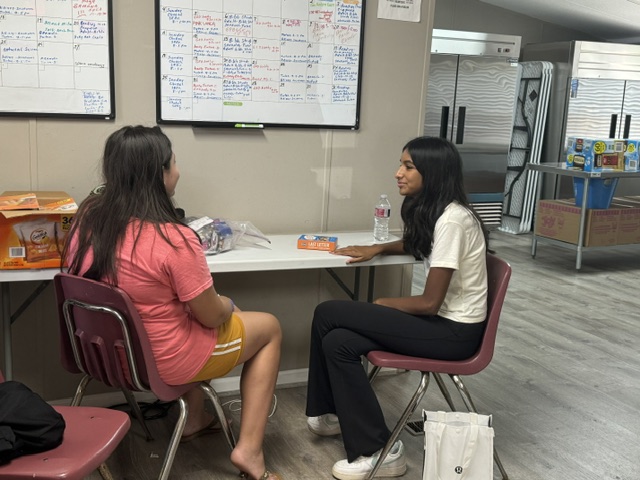 Volunteer tutoring a student one-on-one at a workshop table