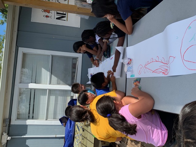 Children drawing together on a long paper banner